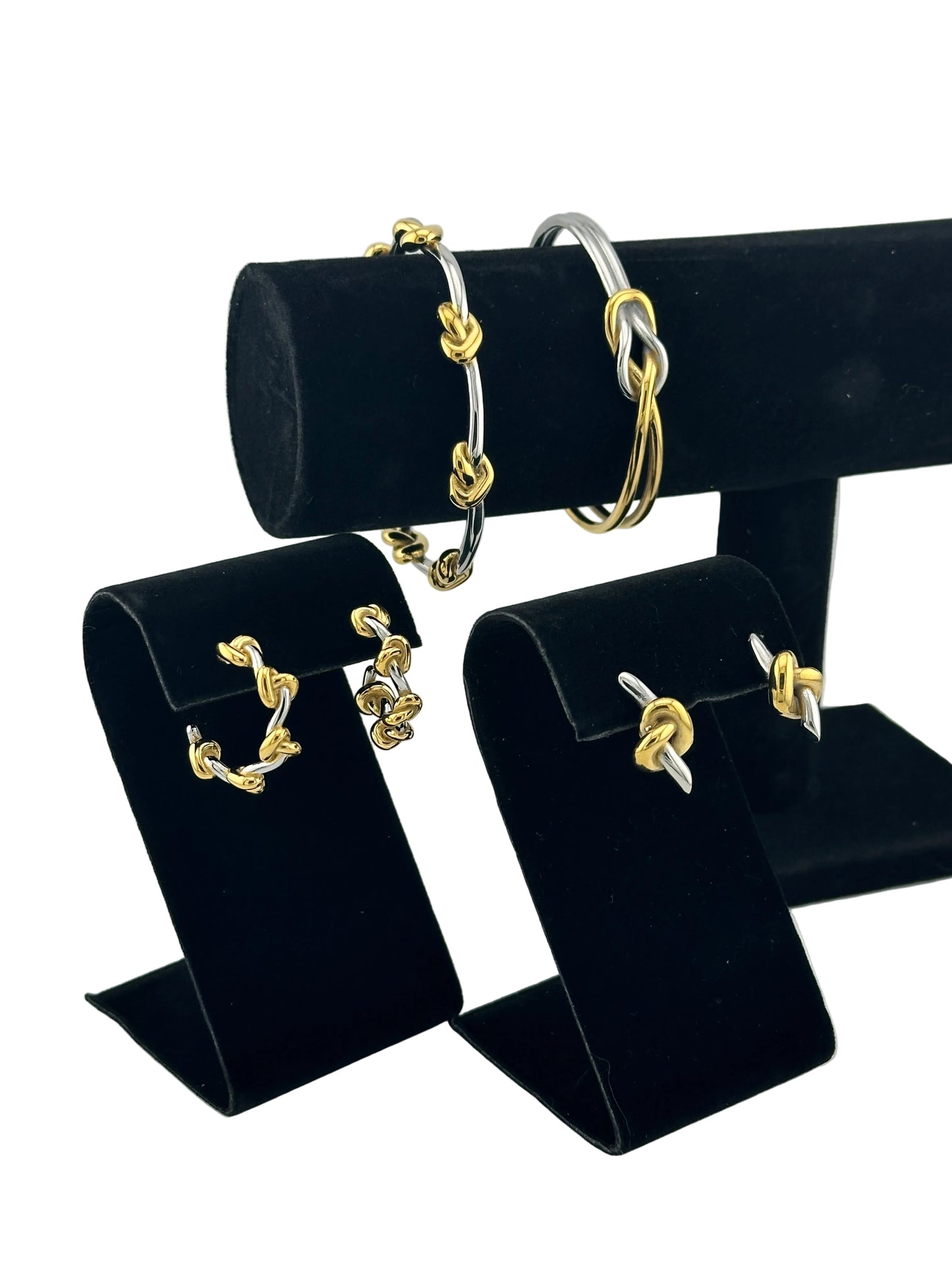 Two gold and silver chain-link rings displayed on black velvet jewelry stands against a light gray background.