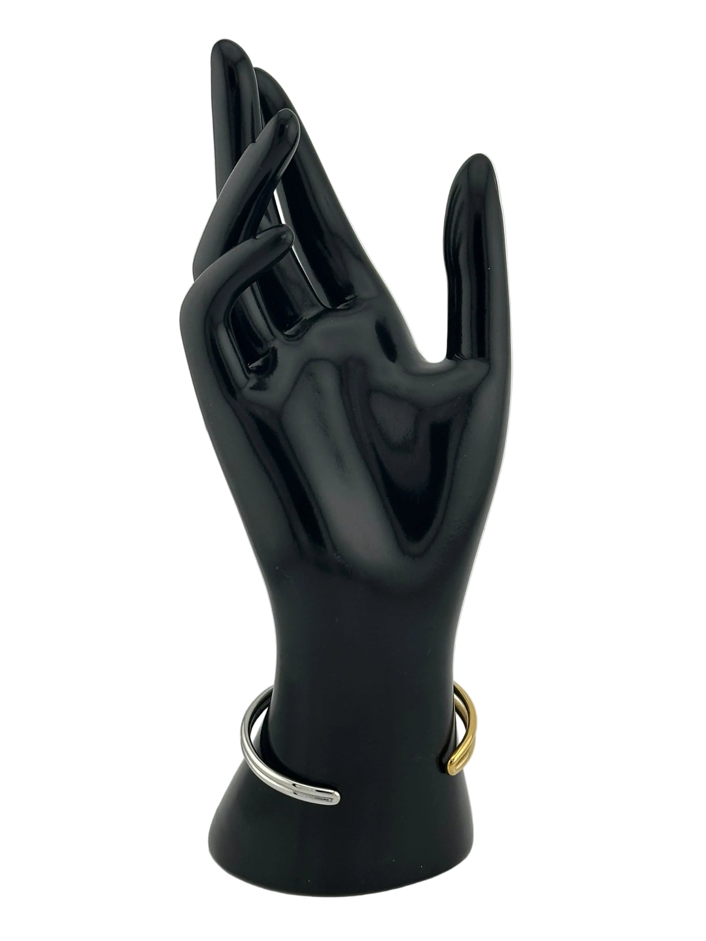 A glossy black hand-shaped wall hook with a gold ring and a silver ring, mounted on a light gray wall.